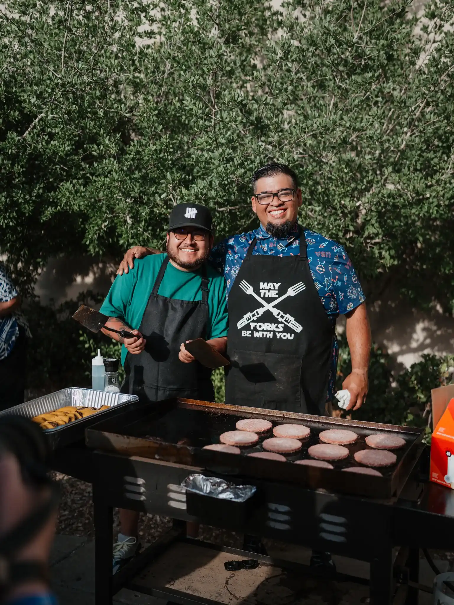 Two serve team members grilling food at a Believer Church event